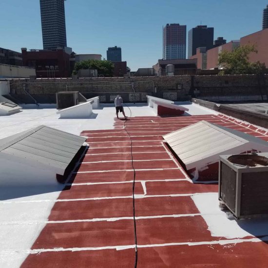 Man performing roof coating services on a building in South Louisiana